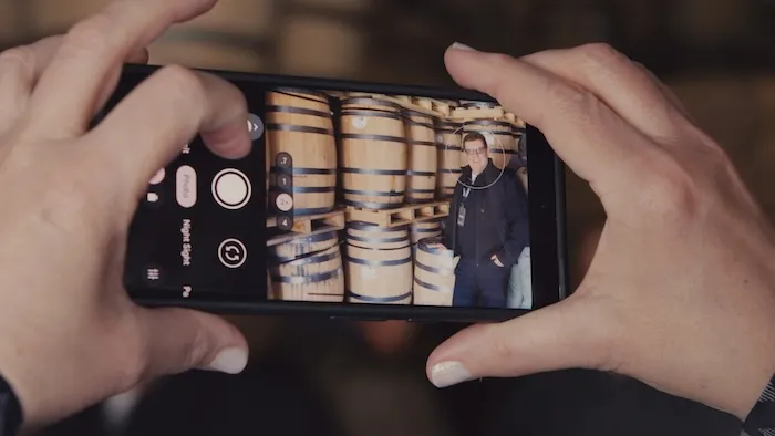 Hands holding a phone in a barrel warehouse